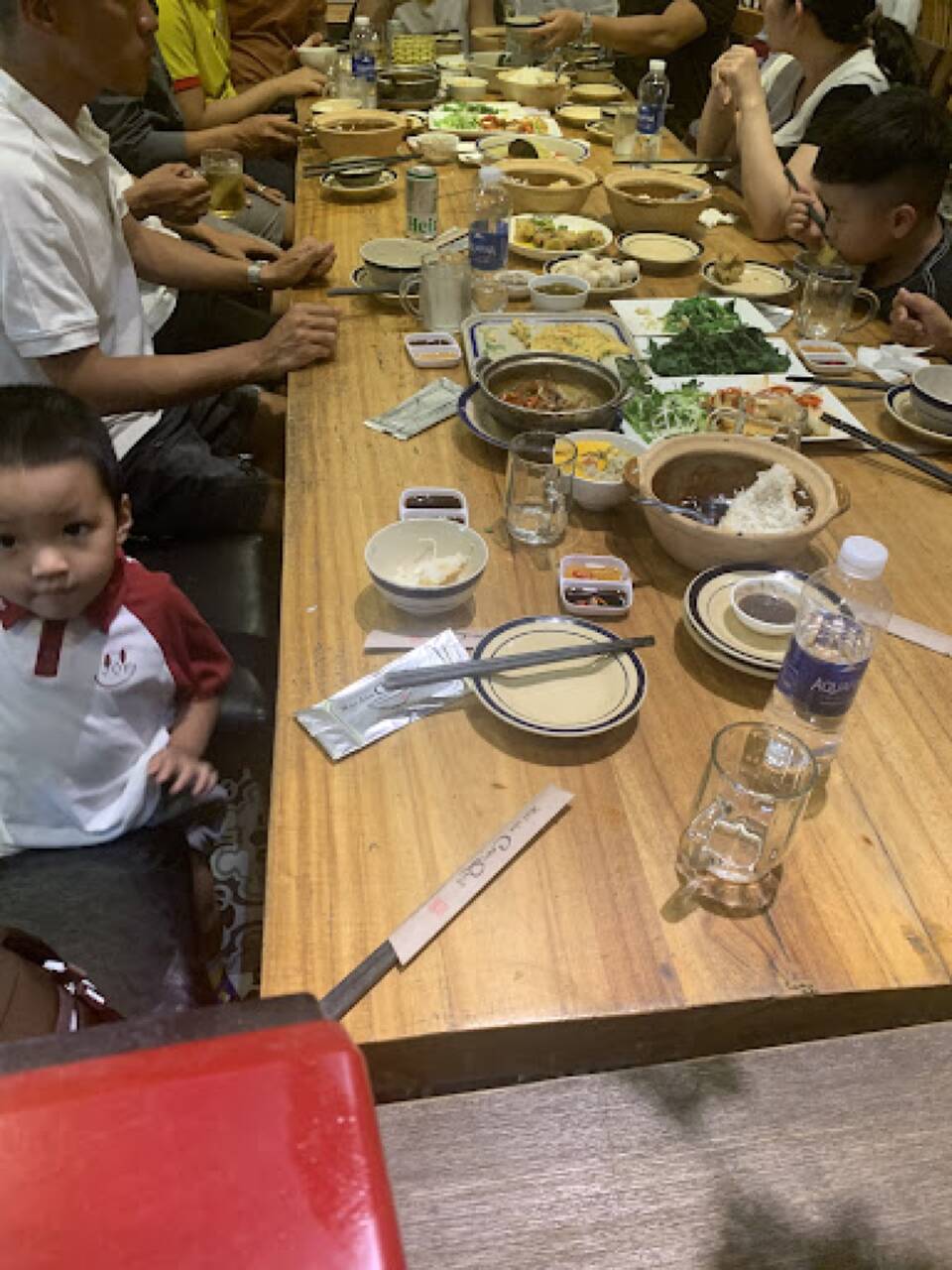 Bàn dài với nhiều nồi cơm niêu, món xào và rau ở Cơm Quê