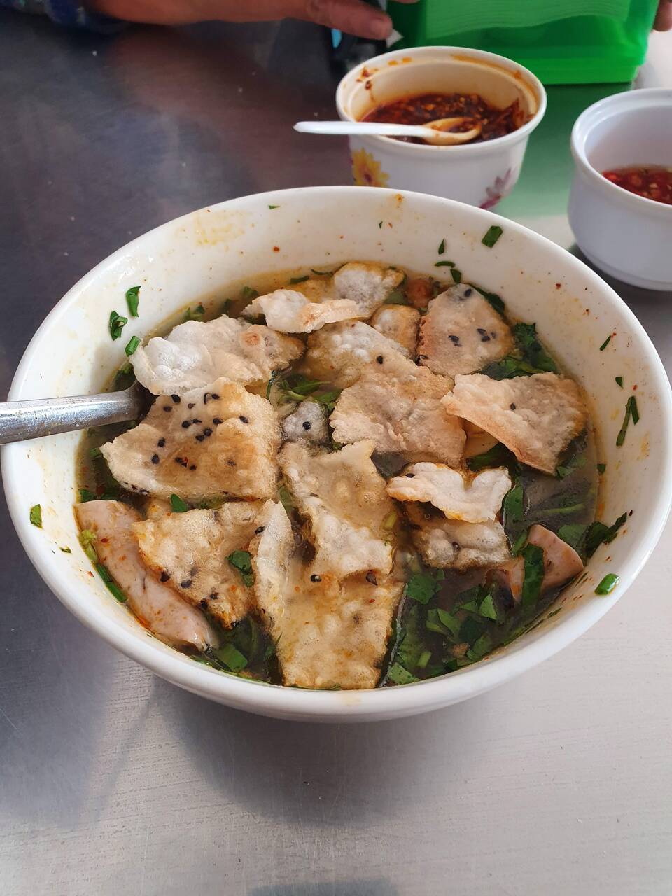 Tô bánh canh chả chiên vàng, nước dùng và rau thơm cạnh chén ớt tại Quán Bánh Canh 32