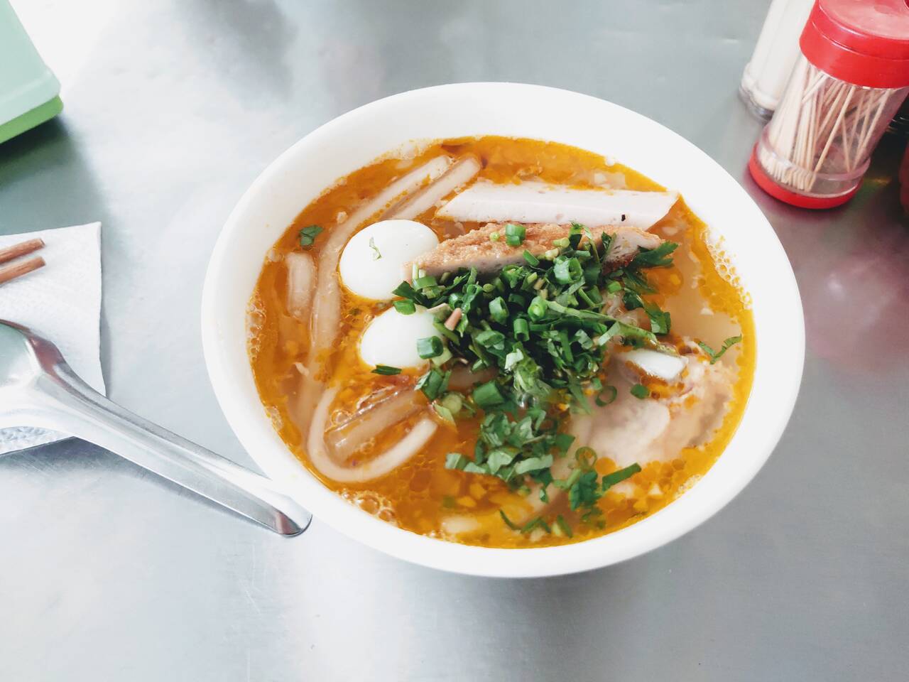 Tô bánh canh nước màu cam có chả cá, trứng cút và hành ngò ở Bánh Canh Cô Bông