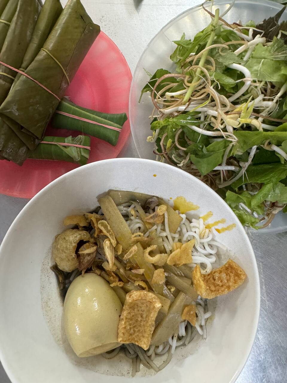 Tô bún cua có trứng và tóp mỡ, nem gói lá và đĩa rau sống tại Bún Cua 19 Phùng Hưng