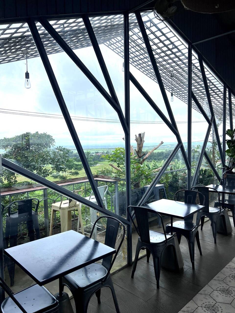 Khung kính ba tầng của Hani Kafe & Kitchen nhìn ra đồng và thành phố ban ngày