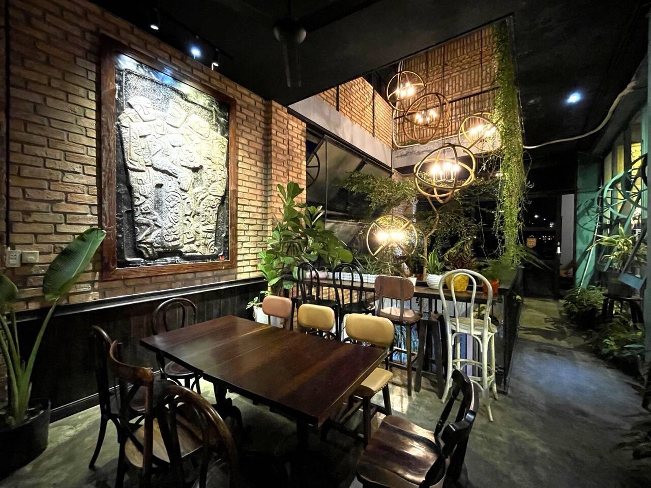 Phòng ăn KAP Bistro với tường gạch, đèn lồng và cây xanh