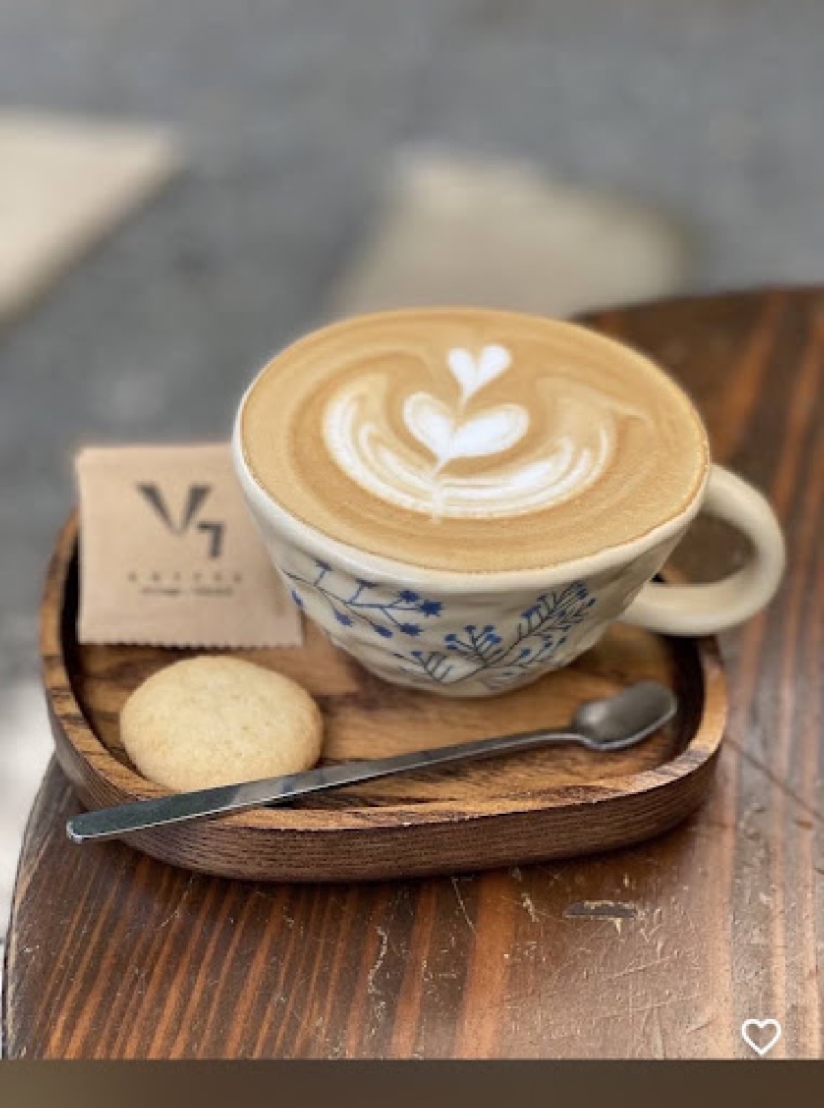 Ly cappuccino vẽ hình lá trên khay gỗ kèm bánh quy tại V7 Coffee
