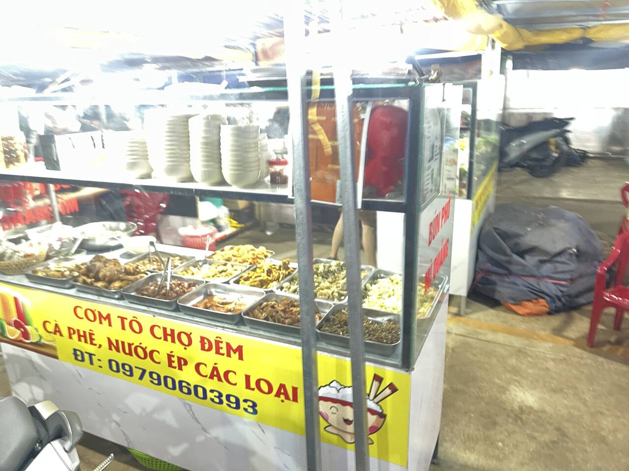 Xe đẩy cơm tô với các khay món xào, bảng ghi cà phê và nước ép các loại