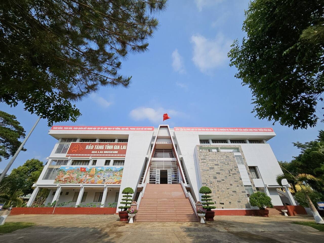 Mặt tiền bảo tàng nhìn từ sân, cầu thang giữa và bức tranh tường phía trái