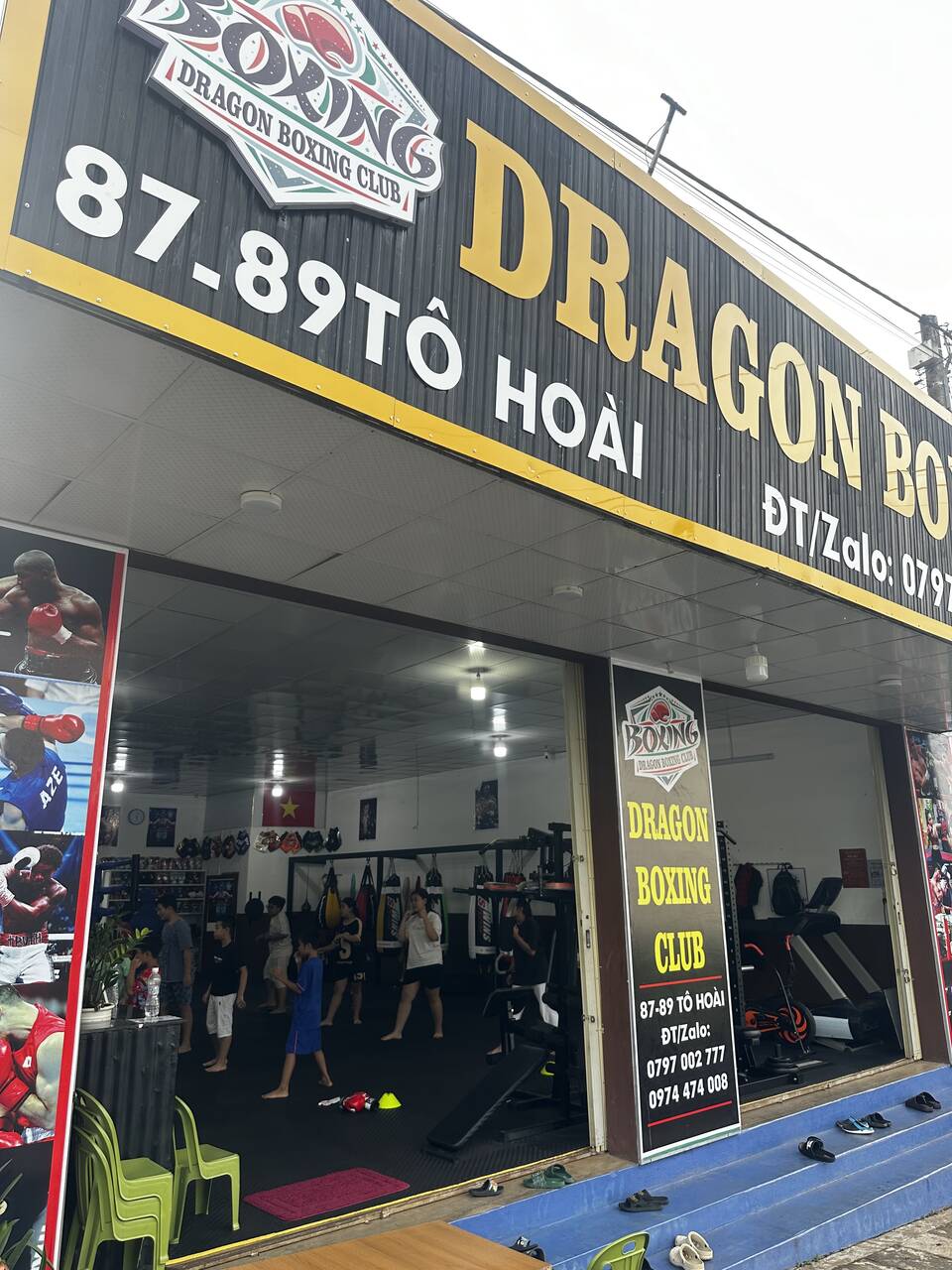 The glass door of Dragon Boxing Club, looking into a training room with heavy bags and people training