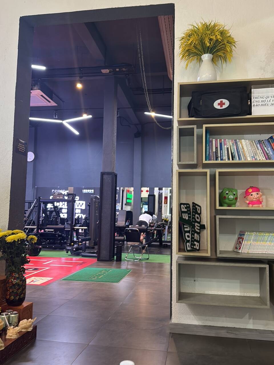 The entrance to the Power Fitness Center training floor, with a bookshelf, a first-aid cabinet and rows of machines behind
