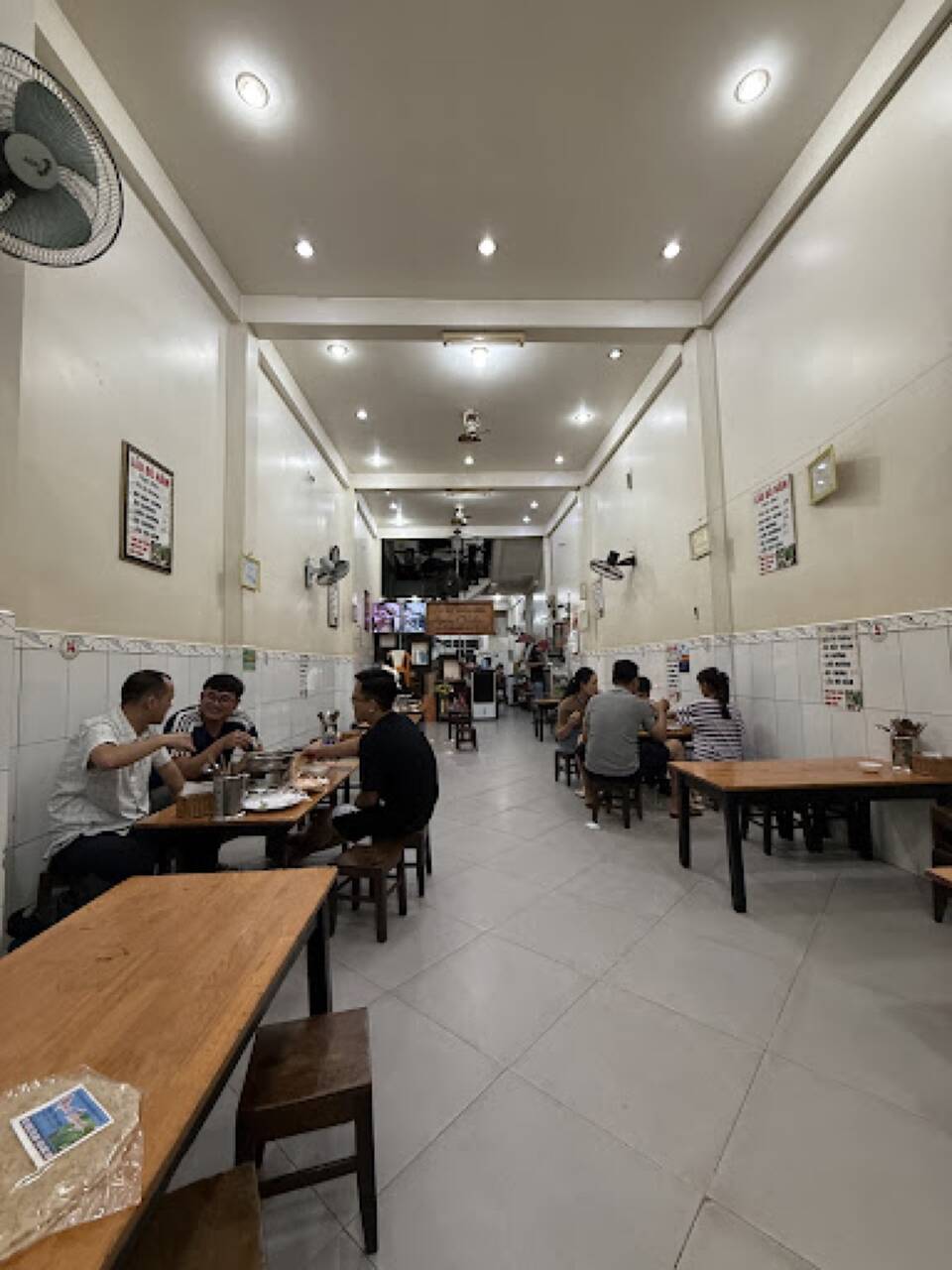 The Anh Chín dining room with long wooden tables and a few groups eating