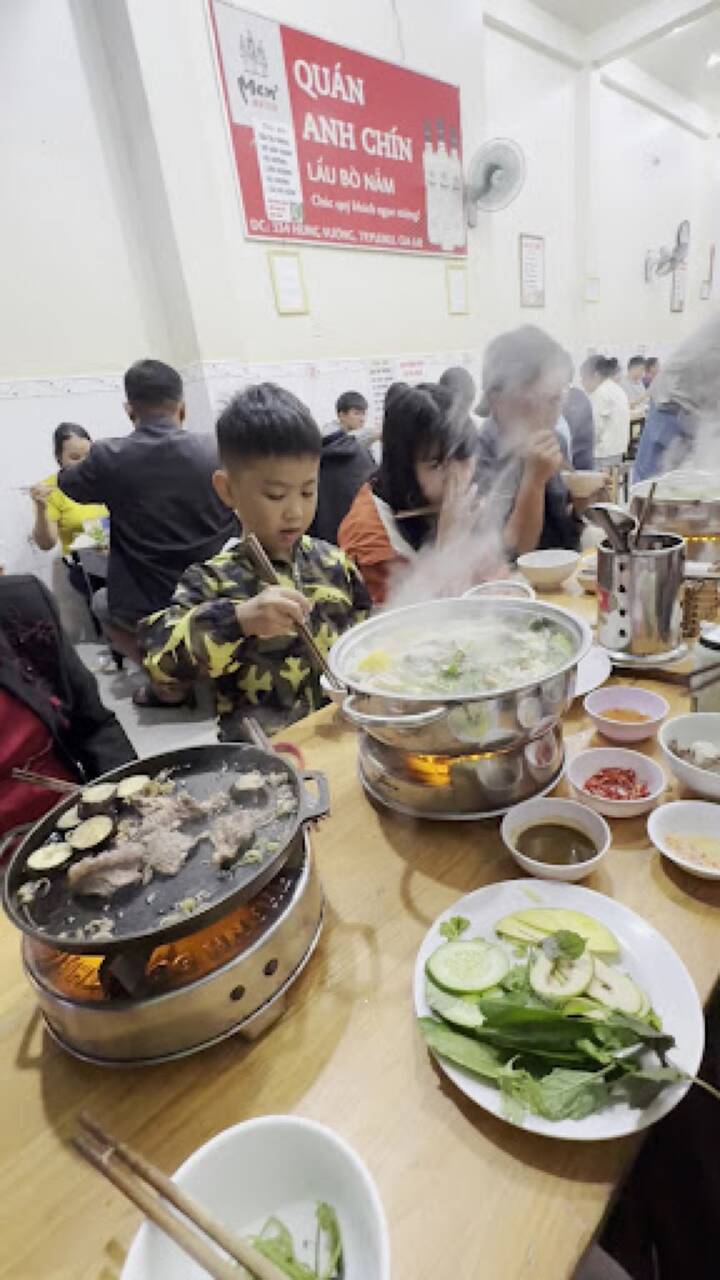 A table with a hotpot and a grill pan under the sign of Anh Chín beef and mushroom hotpot