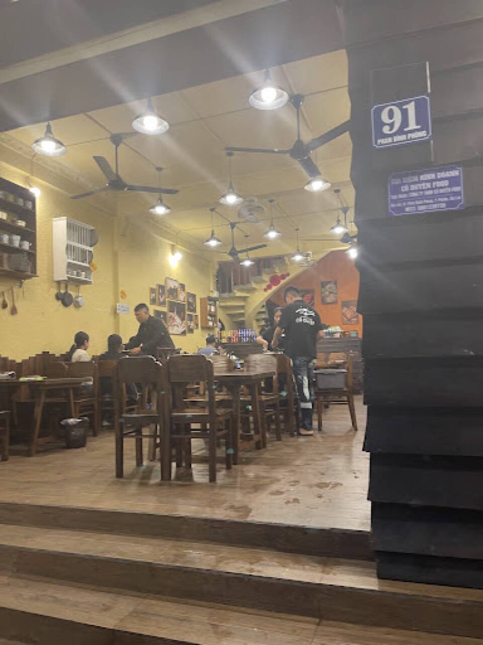 The Lẩu Cô Duyên dining room seen from the door, with wooden tables and chairs and hanging lamps