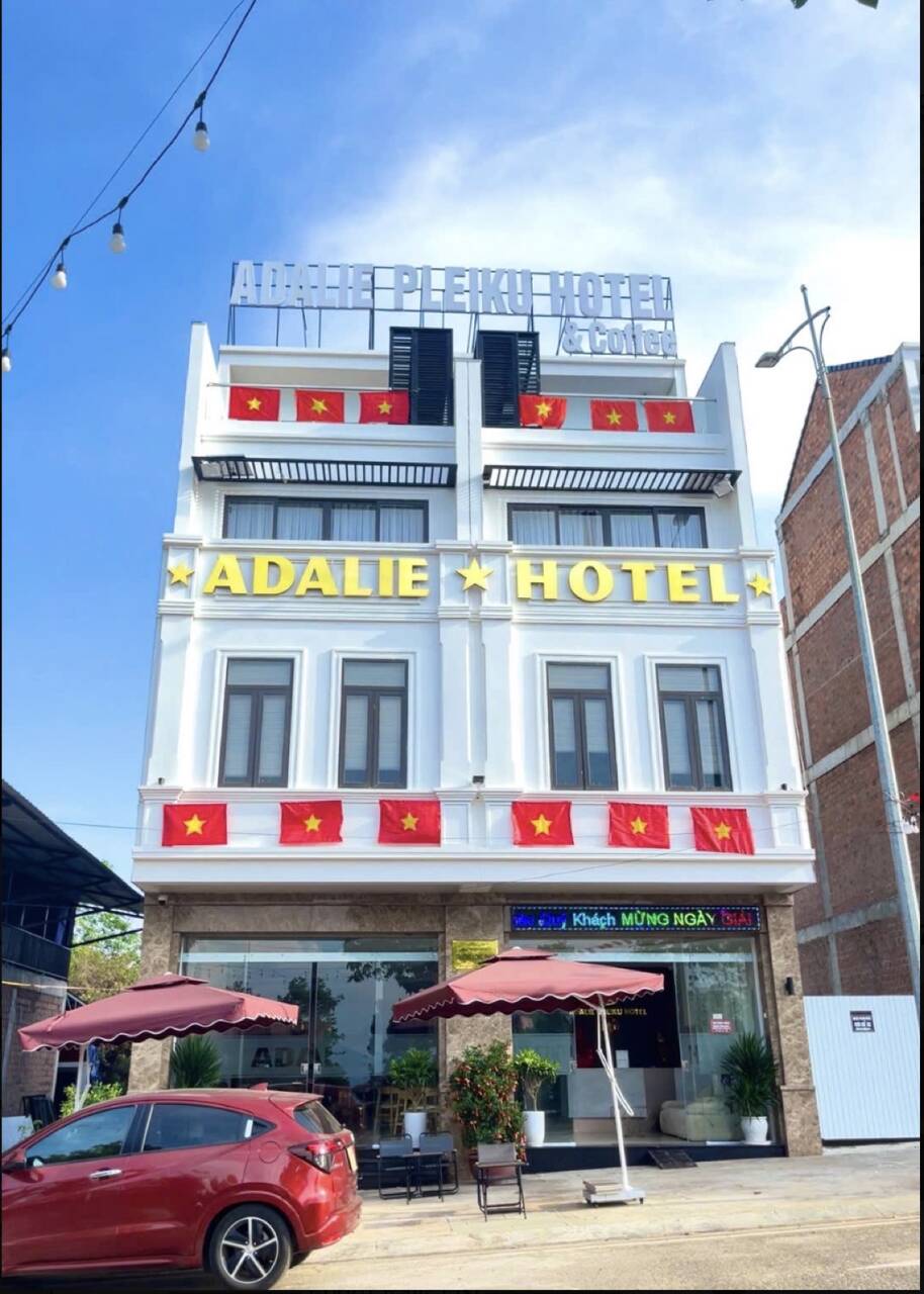 Mặt tiền khách sạn Adalie màu trắng vàng với xe ô tô đậu phía trước