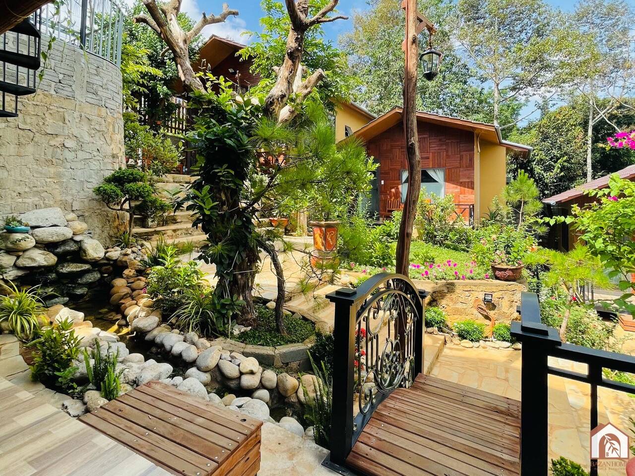 Lối đi lát đá giữa vườn cây cạnh các căn nhà gỗ ở BAZAN HOME