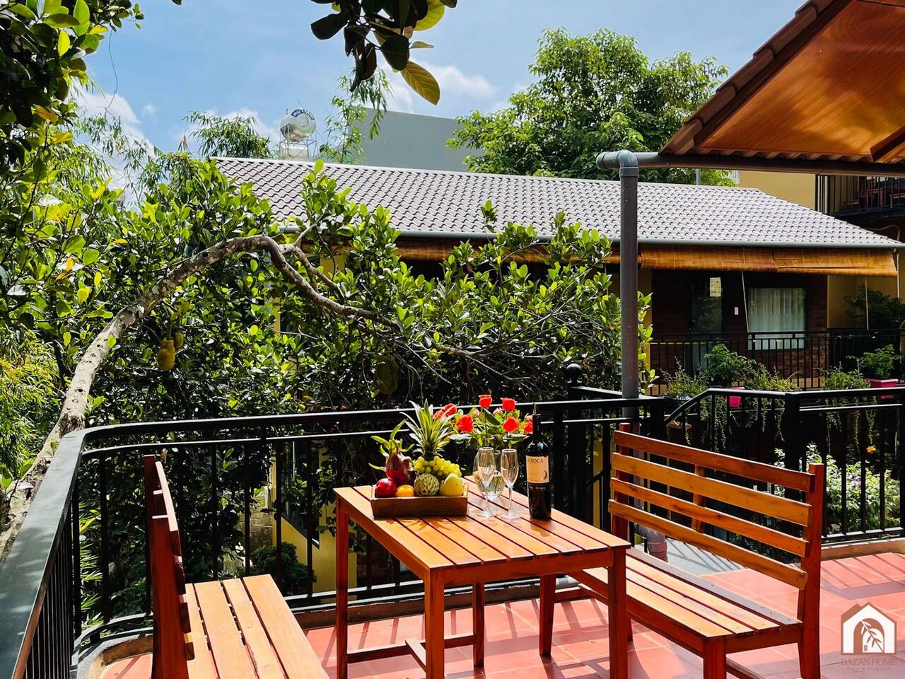 Ban công gỗ có bàn ghế nhìn xuống ao cá ở BAZAN HOME
