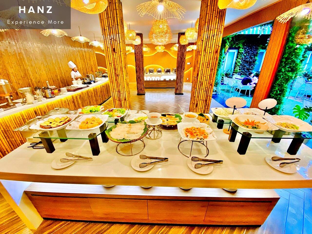 Quầy buffet sáng bày món trong phòng ăn có đèn đan tre