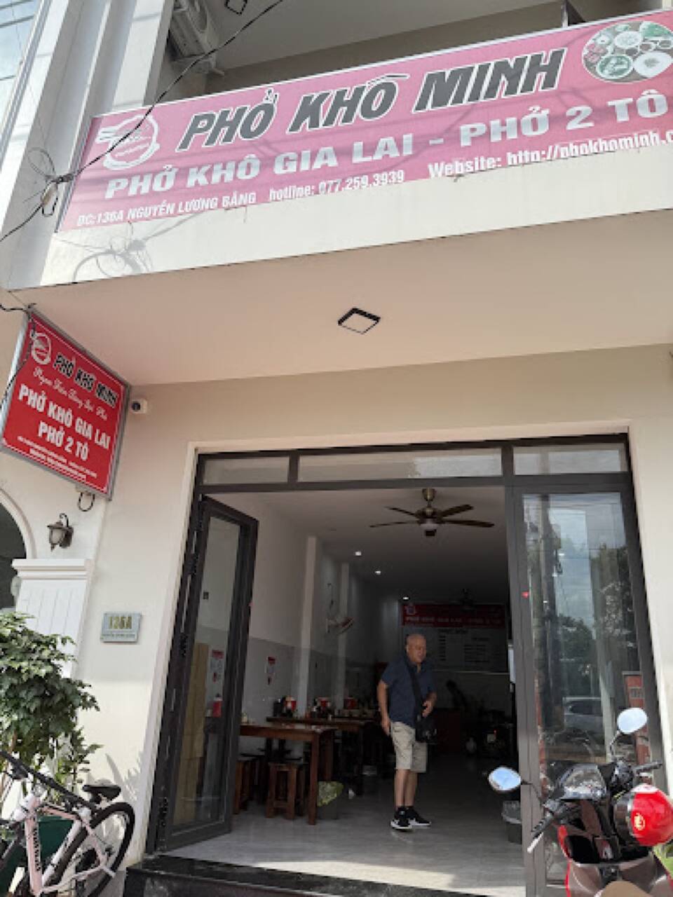 Mặt tiền quán Phở khô Minh ở Nguyễn Lương Bằng với biển hiệu hồng và cửa kính mở
