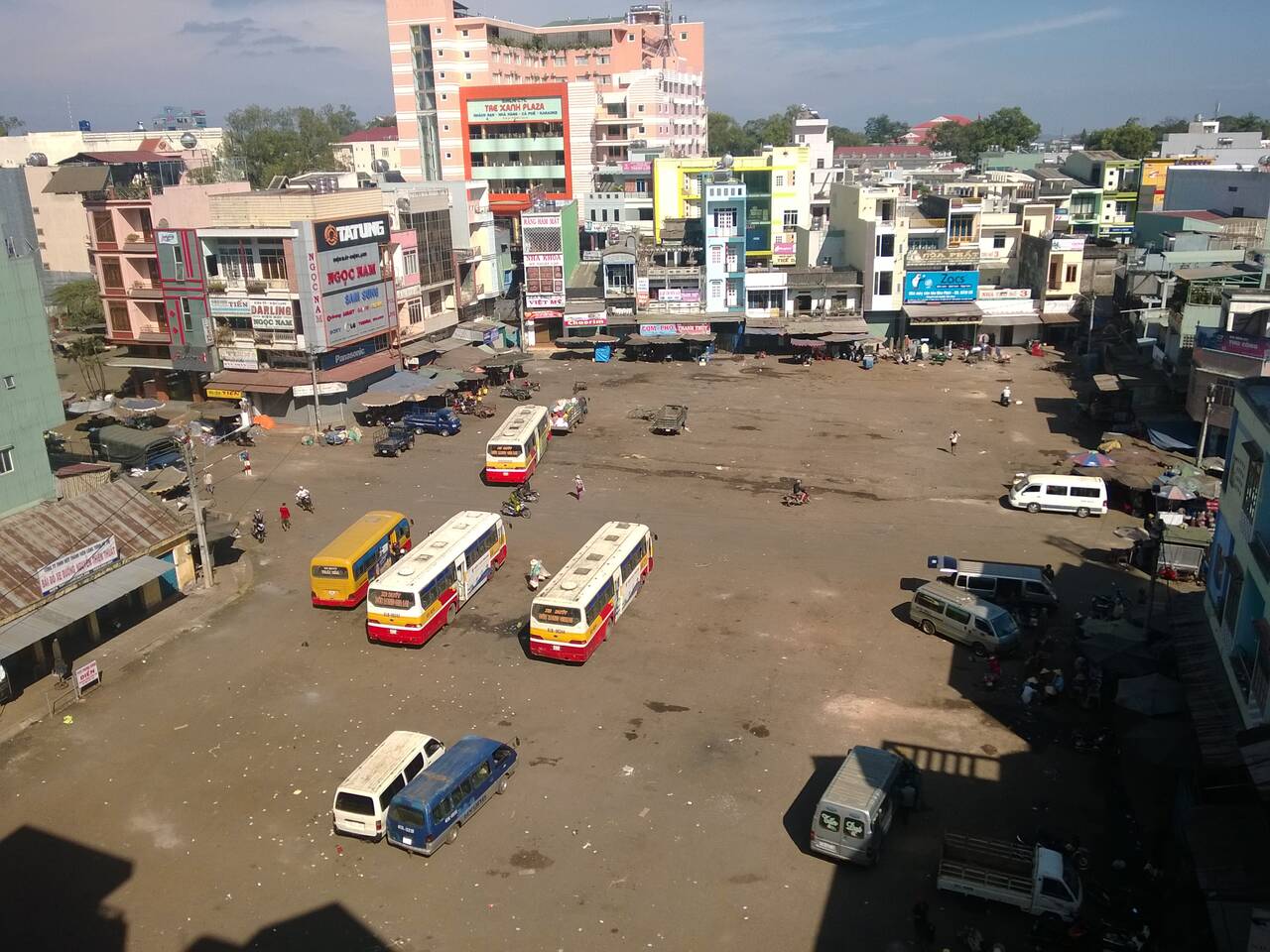 Nhìn từ trên cao xuống một bãi đất rộng có nhiều xe buýt và xe khách đỗ, nhà phố bao quanh