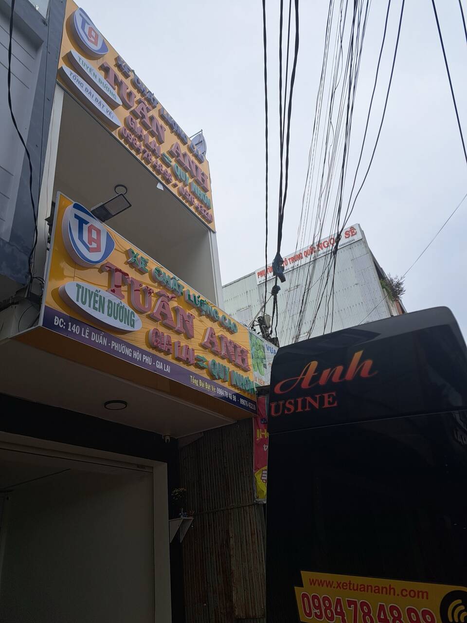 Biển hiệu văn phòng nhà xe Tuấn Anh có số hotline, bên cạnh là xe limousine